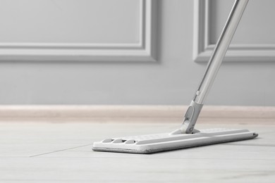 Cleaning of parquet floor with mop indoors, closeup