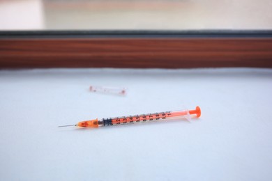 Photo of Disposable syringe with needle on white window sill