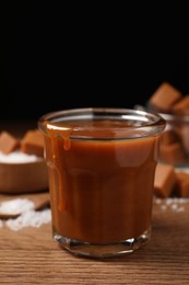 Photo of Tasty salted caramel in glass on wooden table