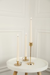 Elegant candlesticks with burning candles on white table