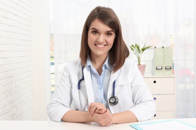 Portrait of pediatrician at table in clinic