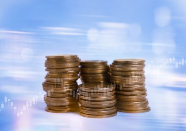 Stacked coins and charts on light blue background