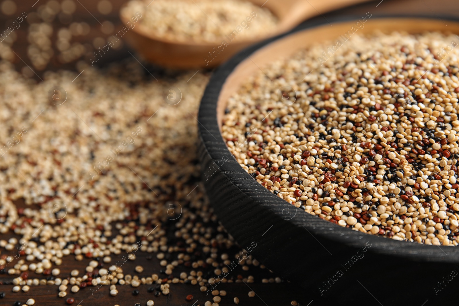 Photo of Plate with mixed quinoa seeds on wooden table, closeup. Space for text