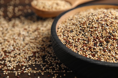 Plate with mixed quinoa seeds on wooden table, closeup. Space for text