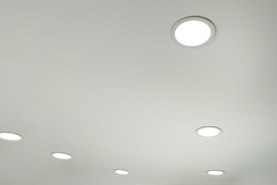 Photo of White ceiling with lamps indoors, below view