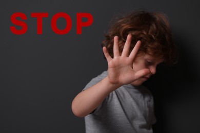 No child abuse. Boy making stop gesture near grey wall, selective focus