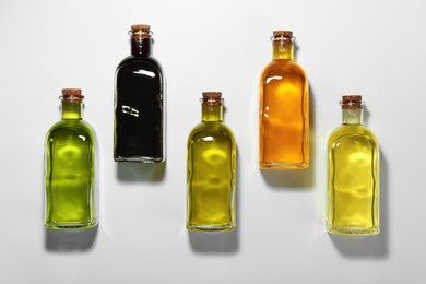 Vegetable fats. Different cooking oils in glass bottles on white background, flat lay