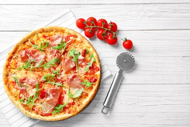 Tasty hot pizza, cherry tomatoes and knife on wooden background, top view