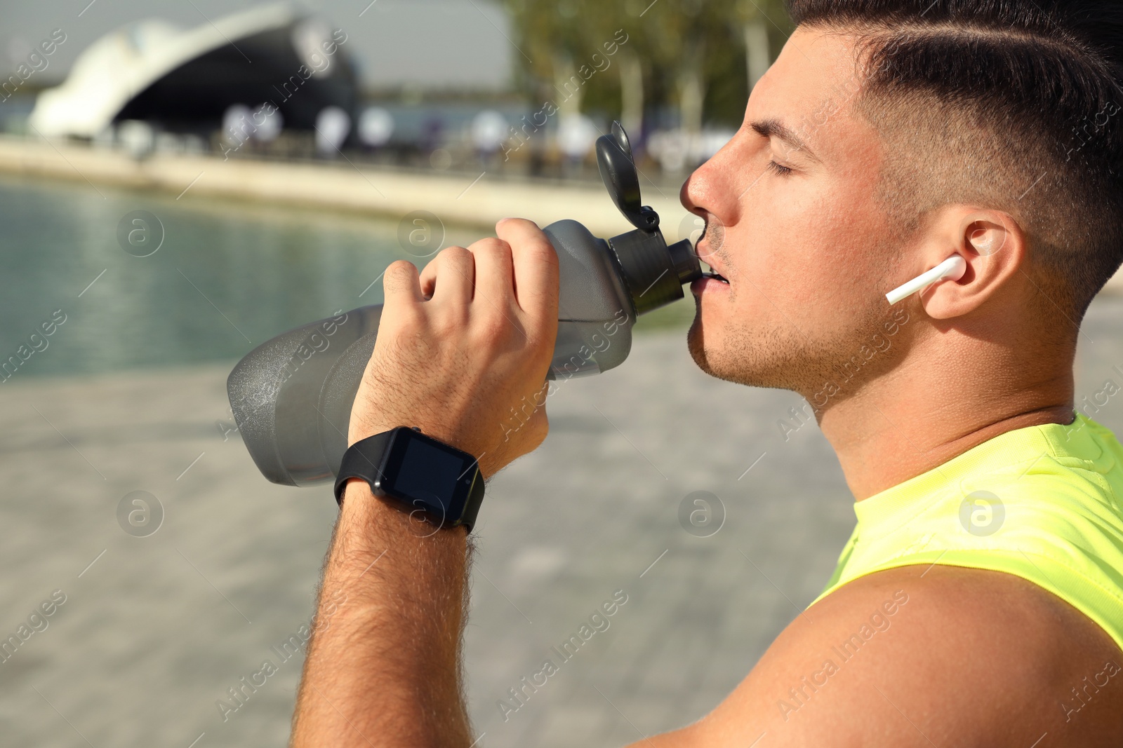 Photo of Man with modern smart watch drinking water outdoors