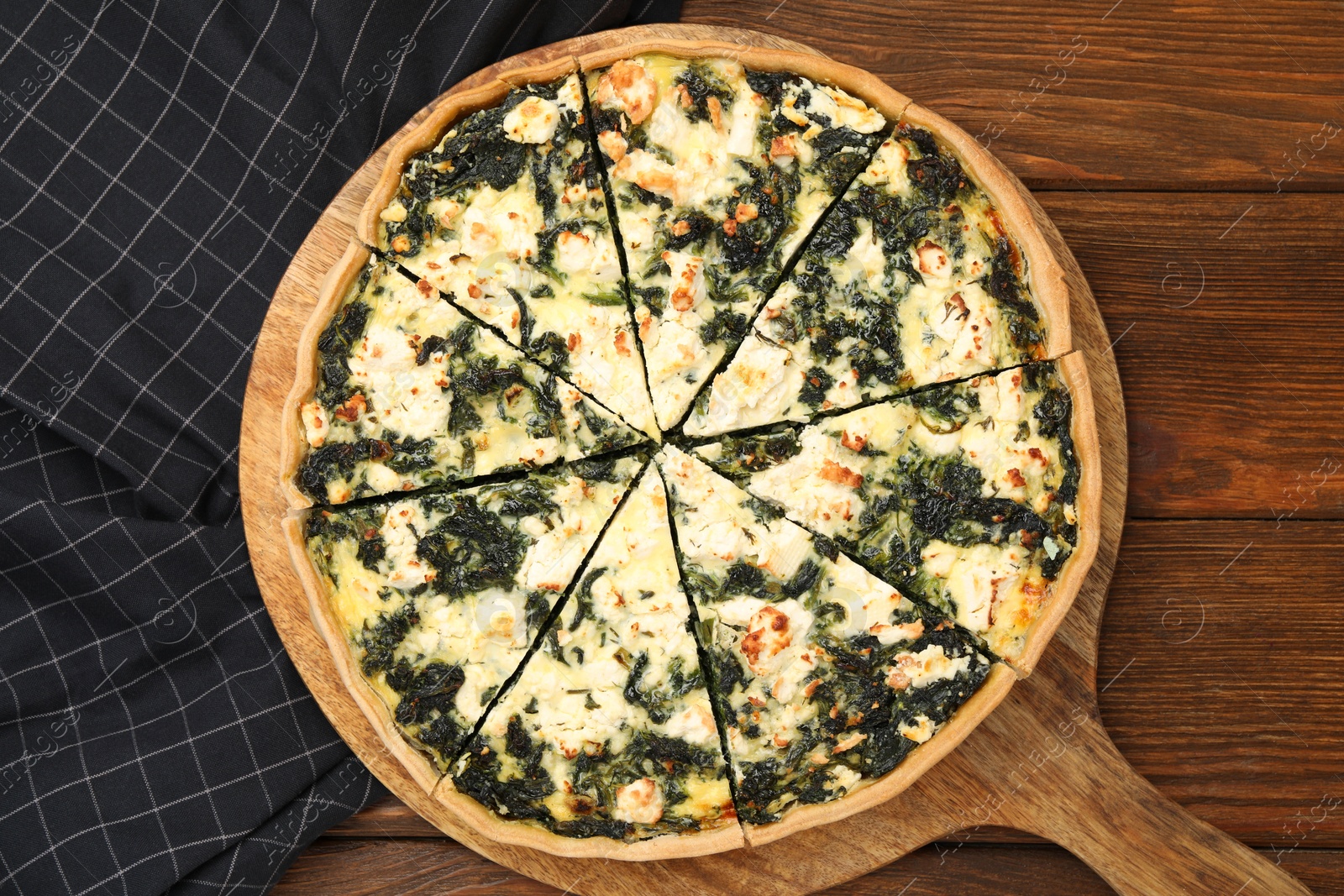 Photo of Delicious homemade spinach quiche on wooden table, top view