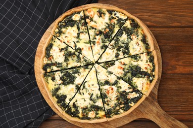 Photo of Delicious homemade spinach quiche on wooden table, top view