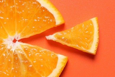 Photo of Slices of juicy orange on terracotta background, top view