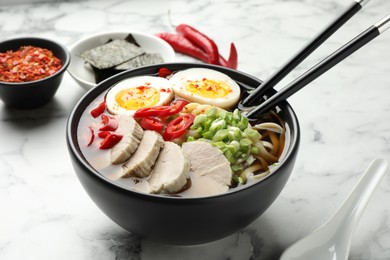 Delicious ramen in bowl on white marble table, closeup. Noodle soup