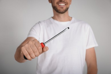 Photo of Happy worker holding screwdriver on white background, closeup