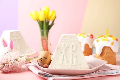 Photo of Traditional cottage cheese Easter paskha and egg with bunny ears on pink wooden table