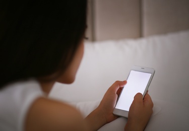 Photo of Young woman with nomophobia using smartphone in bed. Insomnia concept