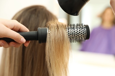 Photo of Stylist drying client's hair in beauty salon, closeup