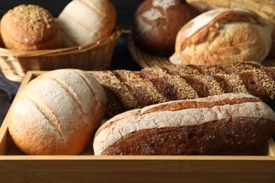 Photo of Baskets with different types of fresh bread on table, closeup