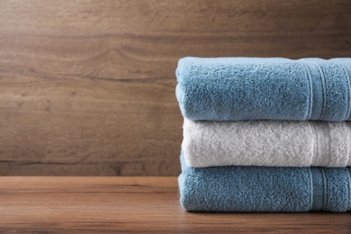 Photo of Stacked soft towels on wooden table. Space for text