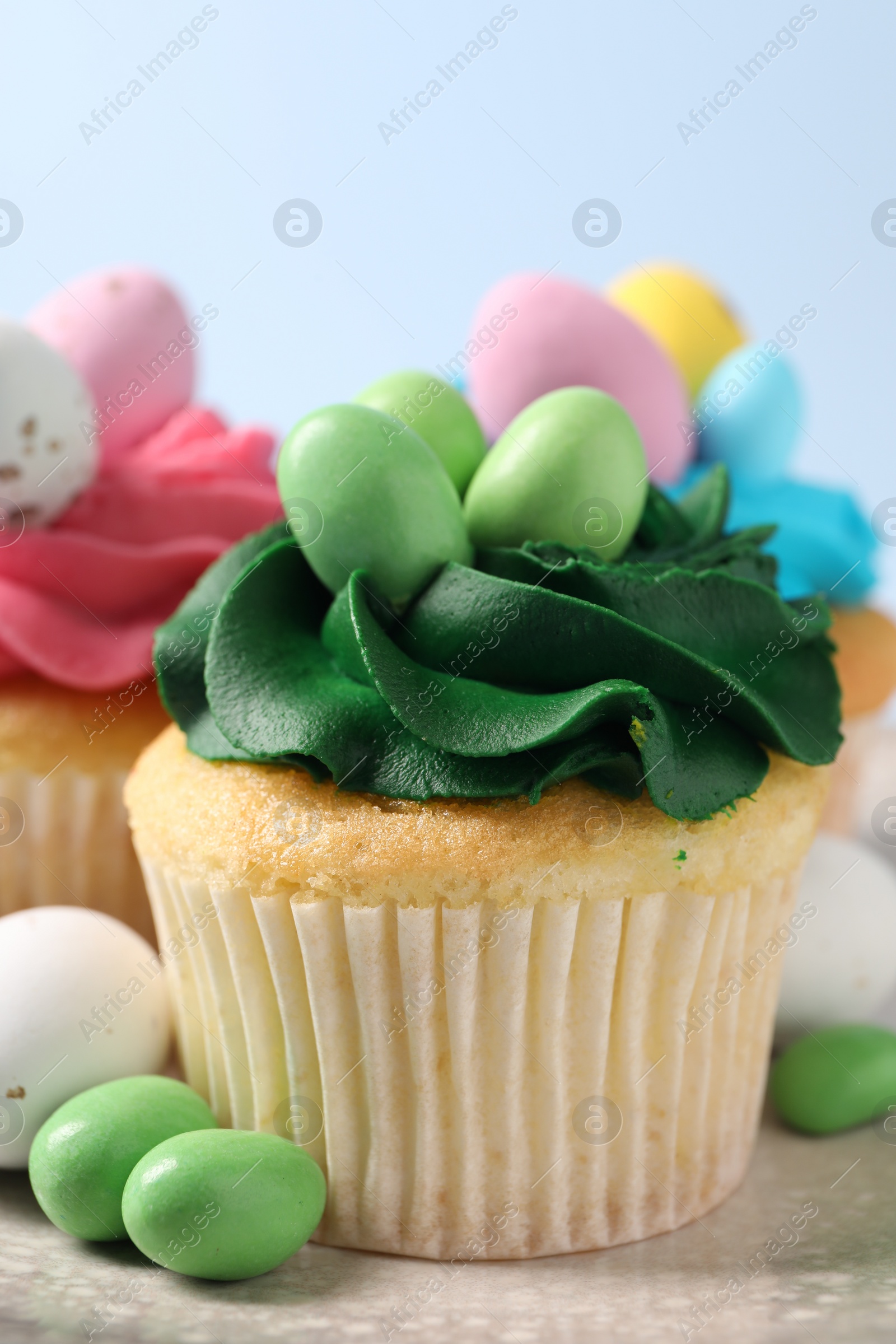 Photo of Tasty cupcakes with Easter decor on light blue background, closeup