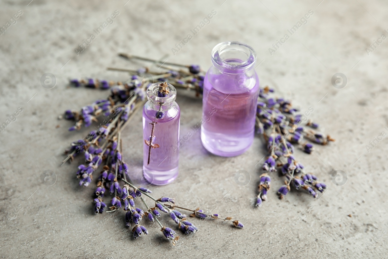 Photo of Natural herbal oil in glass bottles and lavender flowers on color background