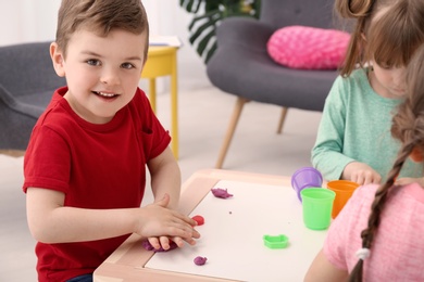 Photo of Cute little children using play dough at table indoors