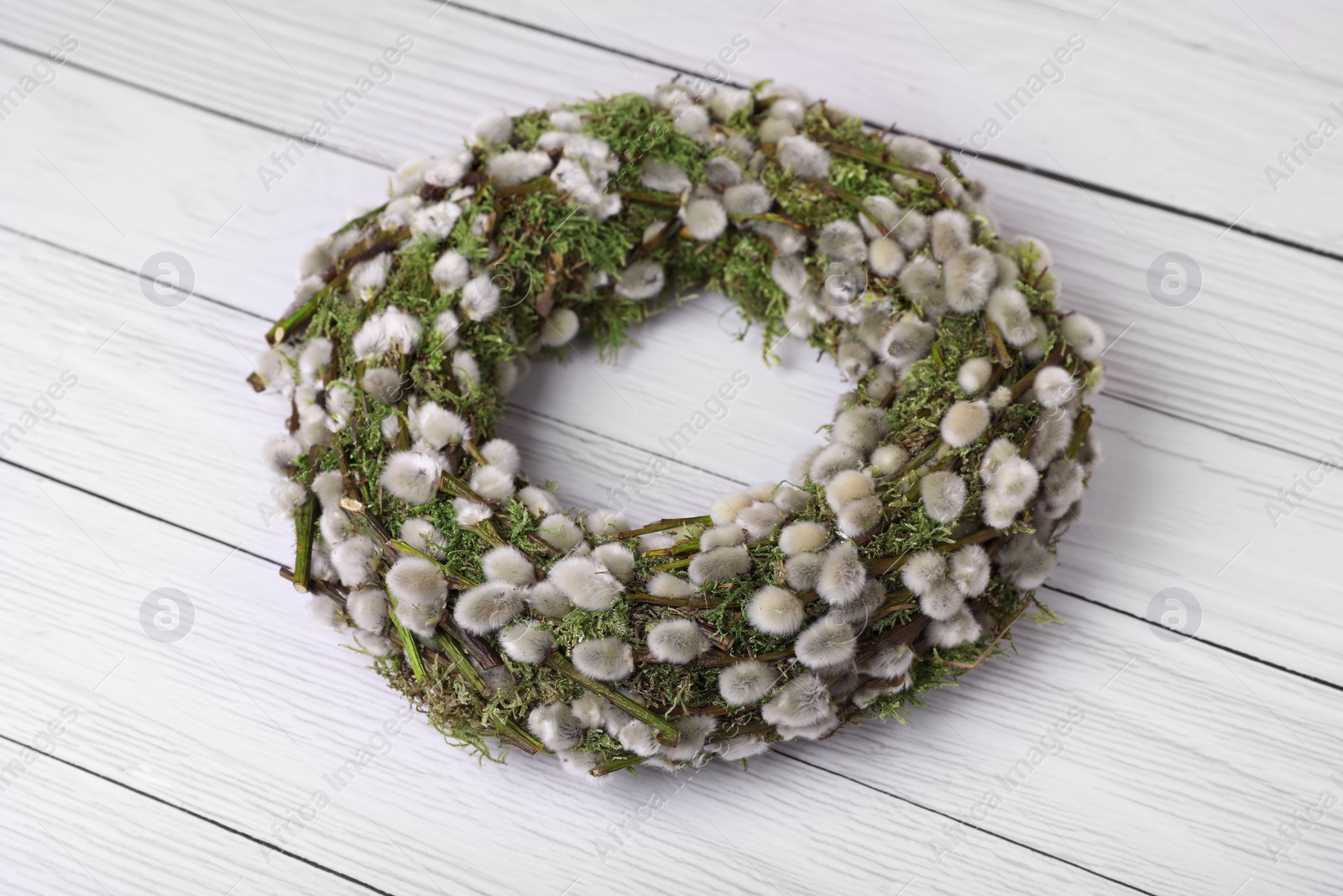 Photo of Wreath made of beautiful willow flowers on white wooden table