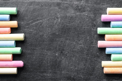 Pieces of color chalk on blackboard, flat lay. Space for text