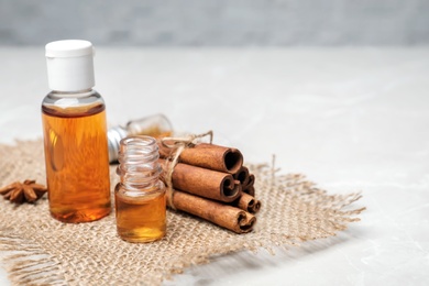 Bottles with cinnamon oil and sticks on table