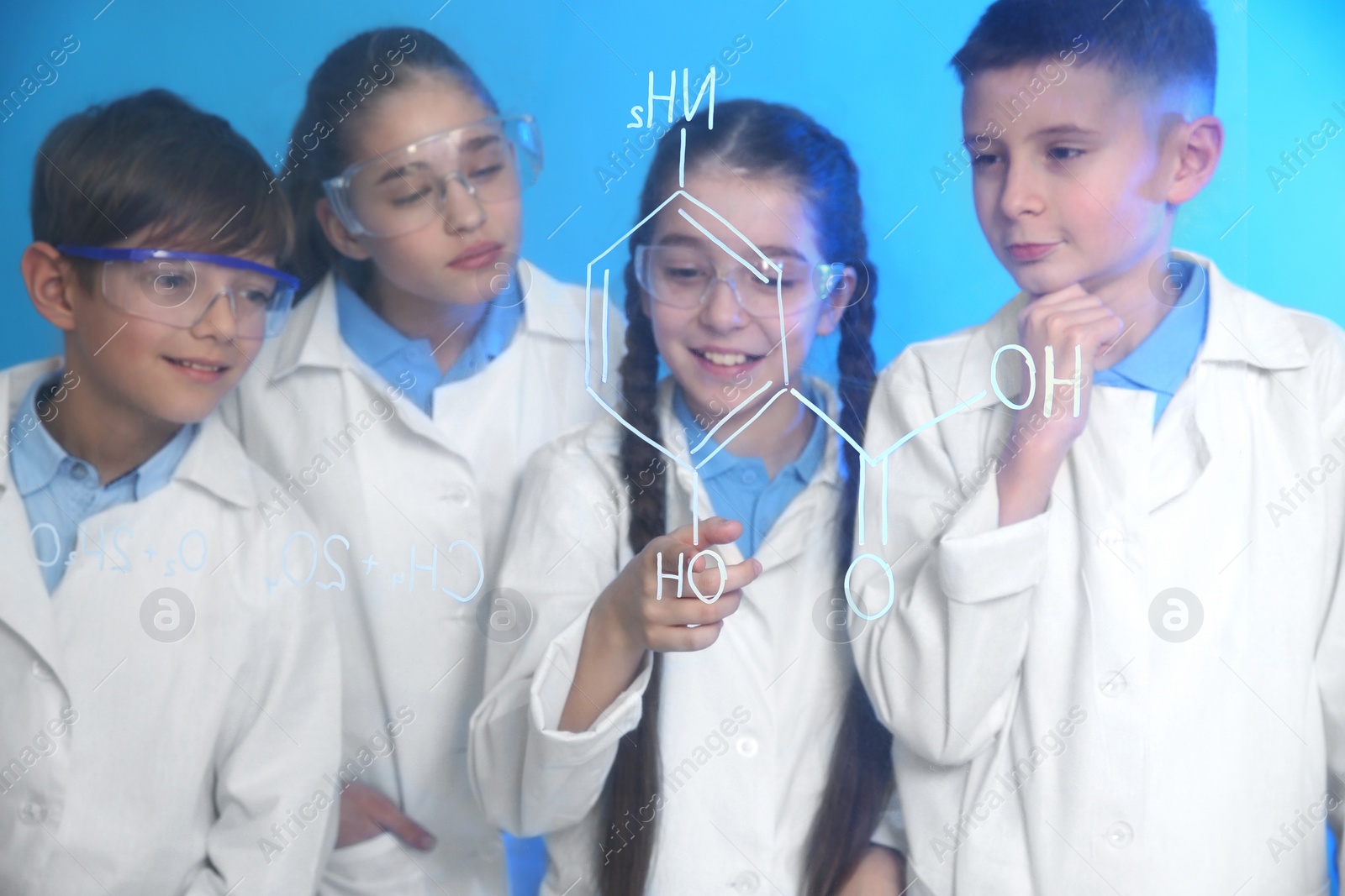 Photo of Pupils studying chemistry formula on glass board against color background