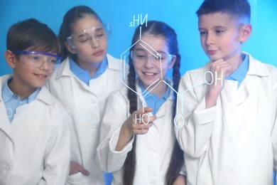 Pupils studying chemistry formula on glass board against color background