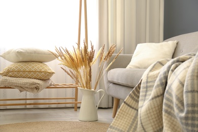 Photo of Vase of dry plants in living room. Interior design