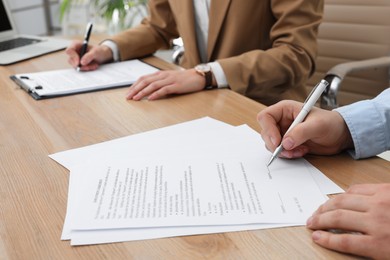 Man signing employment agreement at table in office, closeup. Work contract