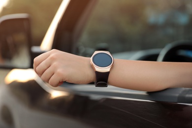 Photo of Young woman with smart watch in car, closeup