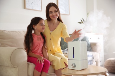 Photo of Mother and daughter near modern air humidifier at home