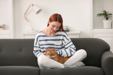 Photo of Happy woman with her cute cat on sofa at home