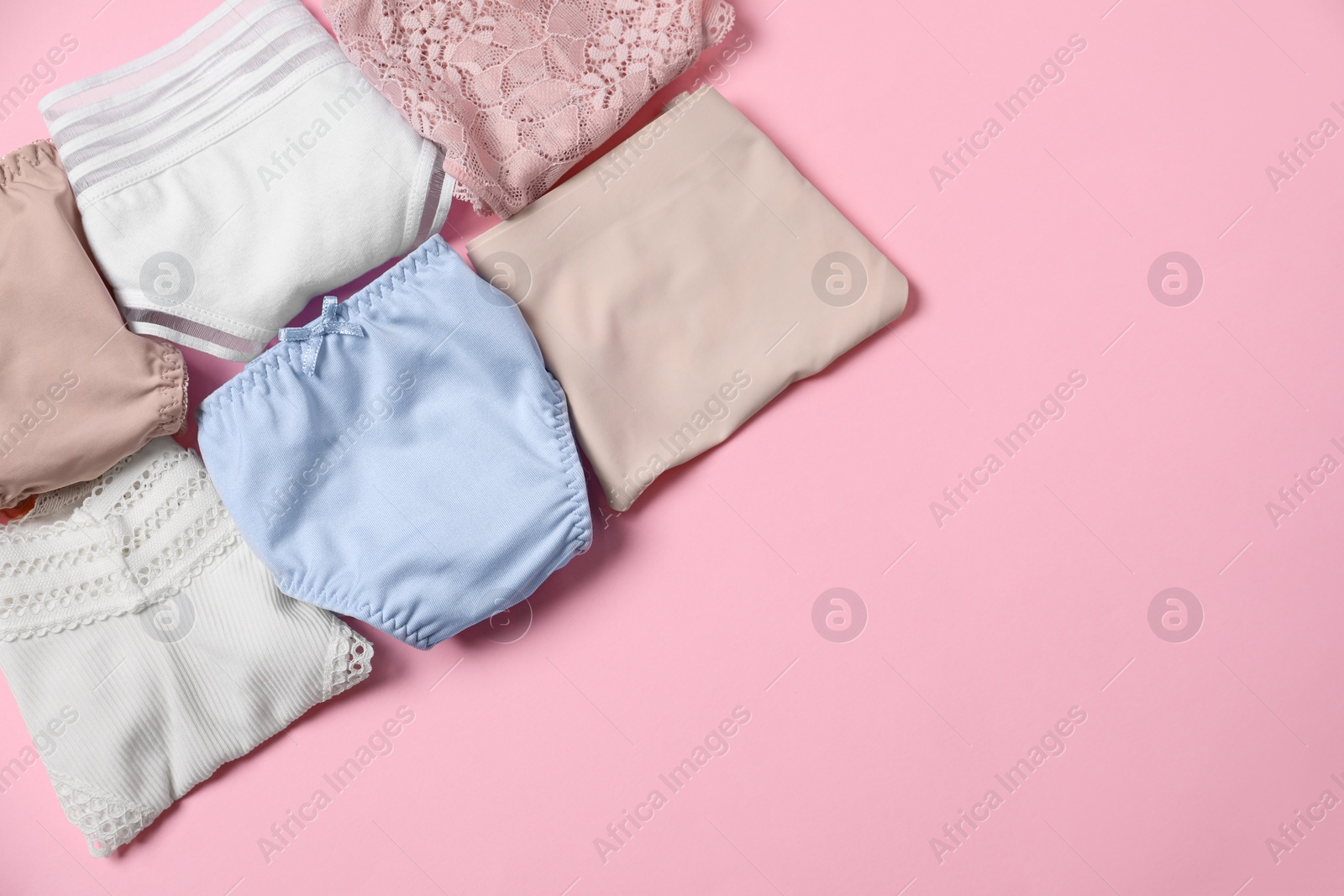 Photo of Stylish folded women's underwear on pink background, flat lay. Space for text