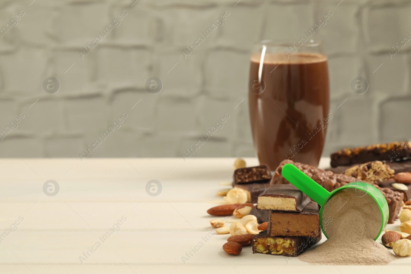 Photo of Different energy bars, nuts, protein cocktail and powder on white wooden table. Space for text