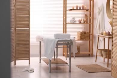 Comfortable massage table with clean towels in spa center