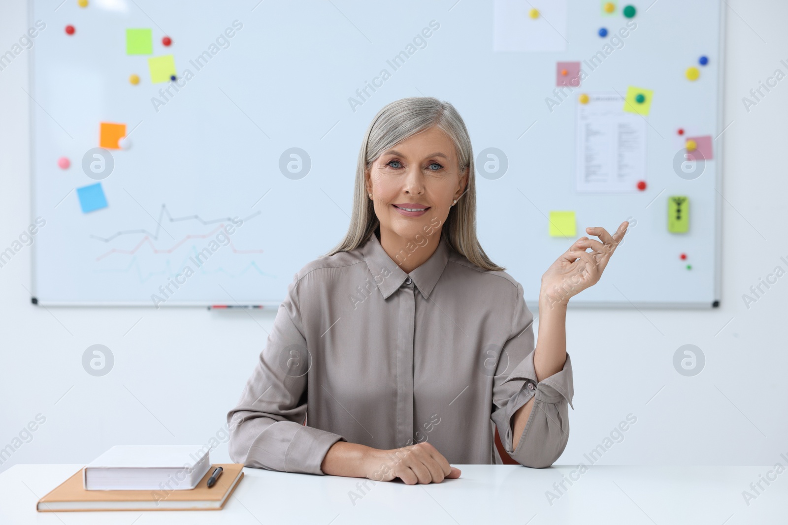 Photo of Happy professor giving lecture at desk in classroom