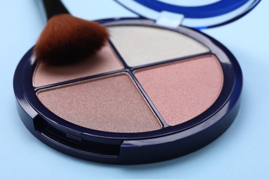 Contouring palette and brush on light blue background, closeup. Professional cosmetic product