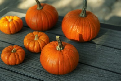 Many whole ripe pumpkins on wooden table outdoors