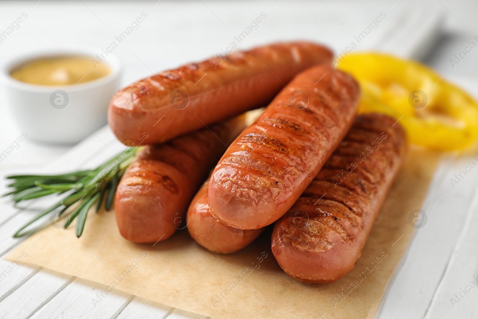 Photo of Delicious grilled sausages on white wooden table, closeup. Barbecue food