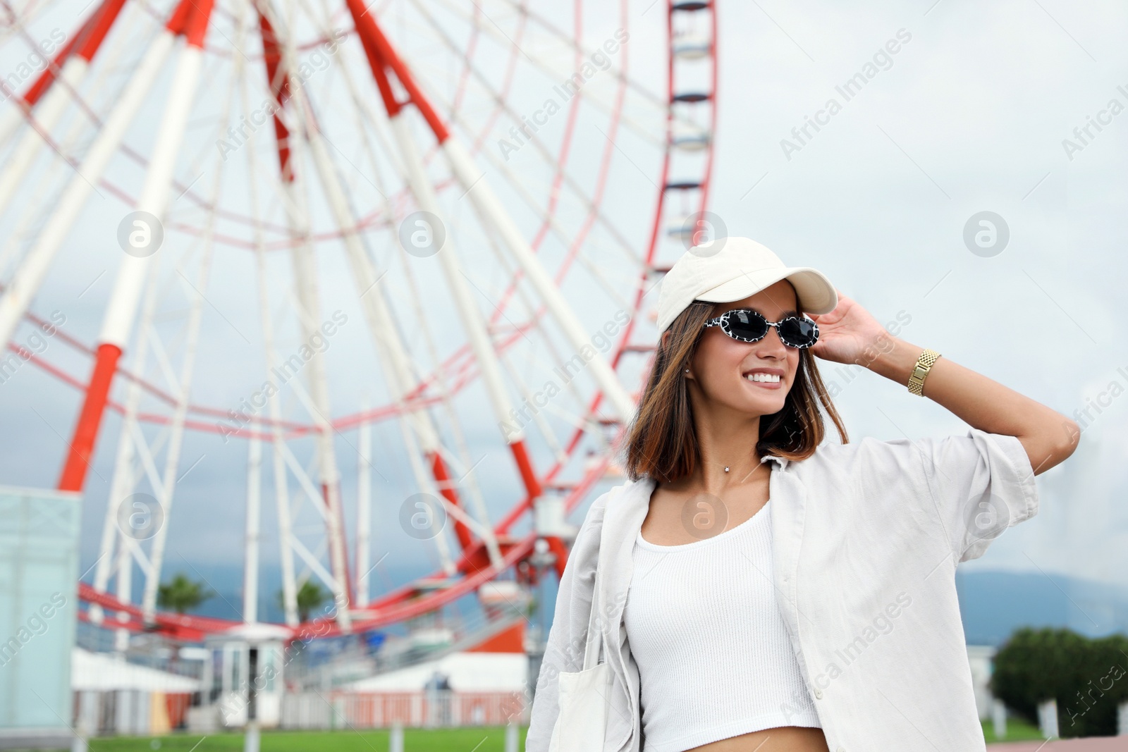 Photo of Beautiful young woman near Ferris wheel outdoors