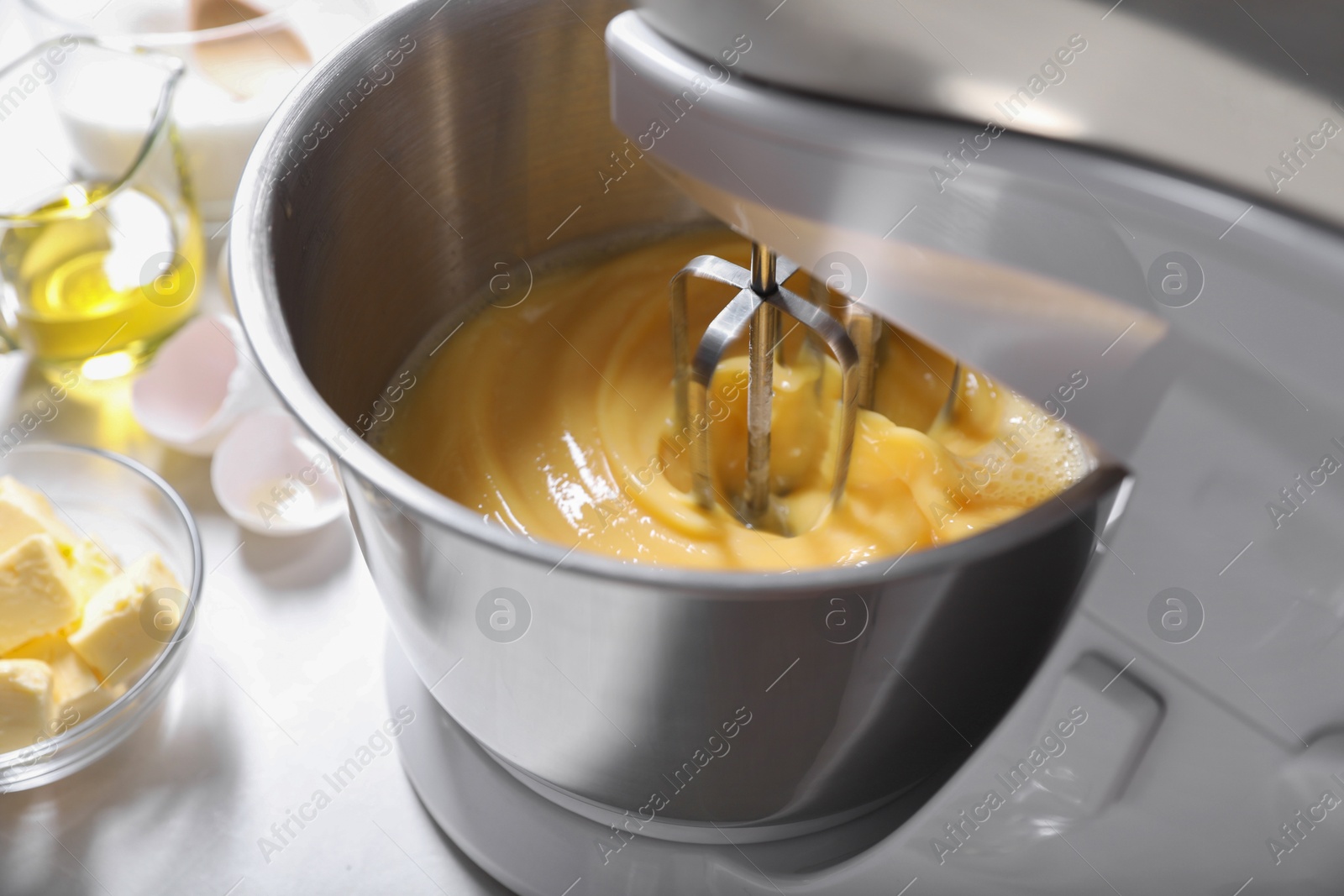 Photo of Making dough in bowl of stand mixer on white table, closeup