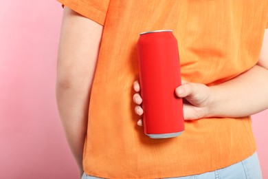 Woman holding red beverage can on pink background, closeup