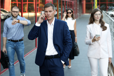 Photo of Different people walking on modern city street