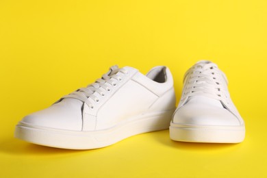 Photo of Pair of stylish white sneakers on yellow background