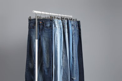 Photo of Rack with different jeans on grey background