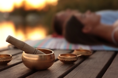 Photo of Couple at healing session outdoors, focus on singing bowl